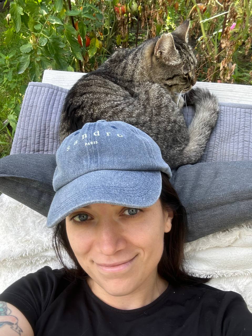 Selfie with a tabby cat perched on top of a denim cap
